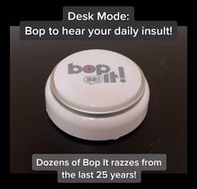 Load and play video in Gallery viewer, Bop it Button Demo - Bop it button on plain dark surface with hand pushing white and silver round button. It demonstrates desk mode where you get a daily insult and then Game mode where you can play Bop It on your own or with others.